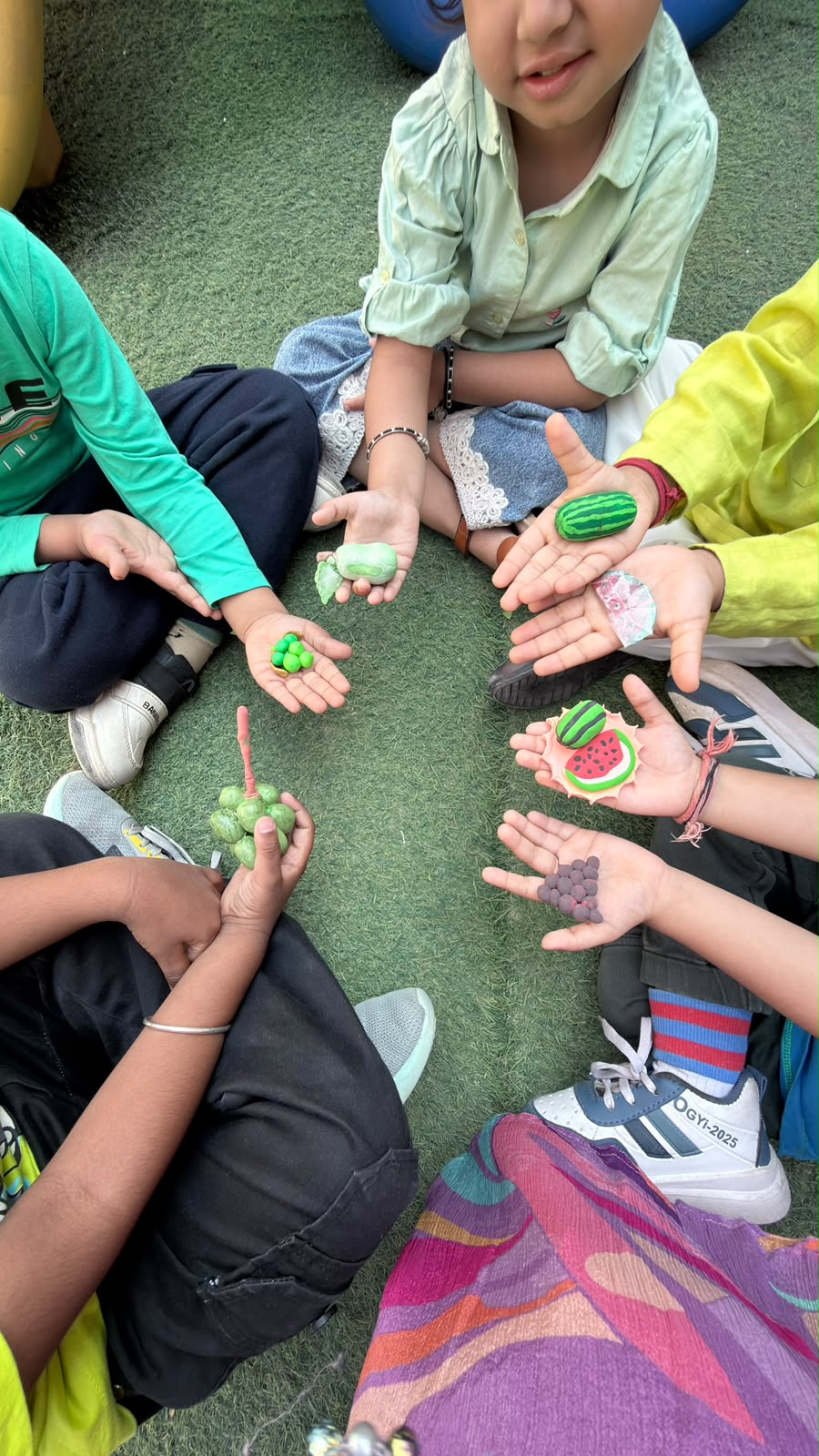 Children's hands holding clay fruit in a circle